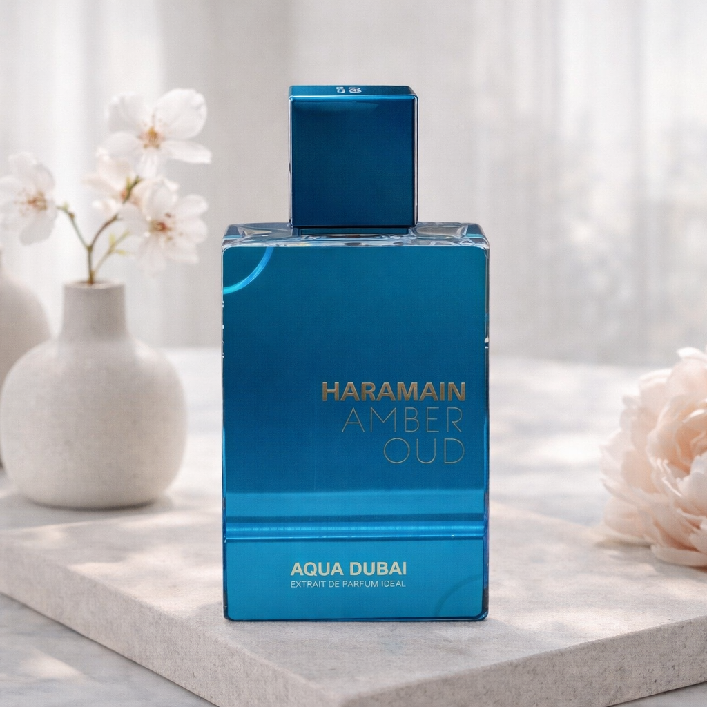 Haramain Amber Oud perfume bottle on a white surface with flowers and vases in the background