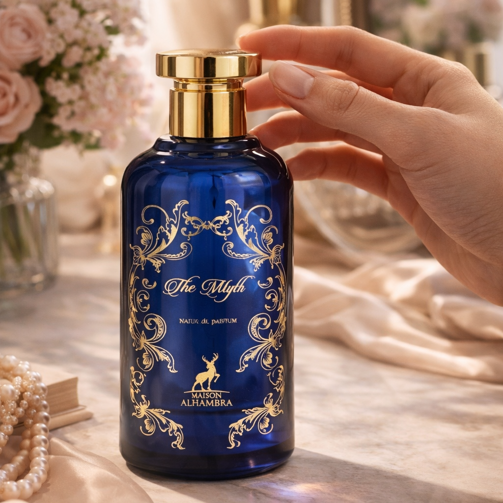 Blue perfume bottle with gold accents held by a hand on a decorative surface.
