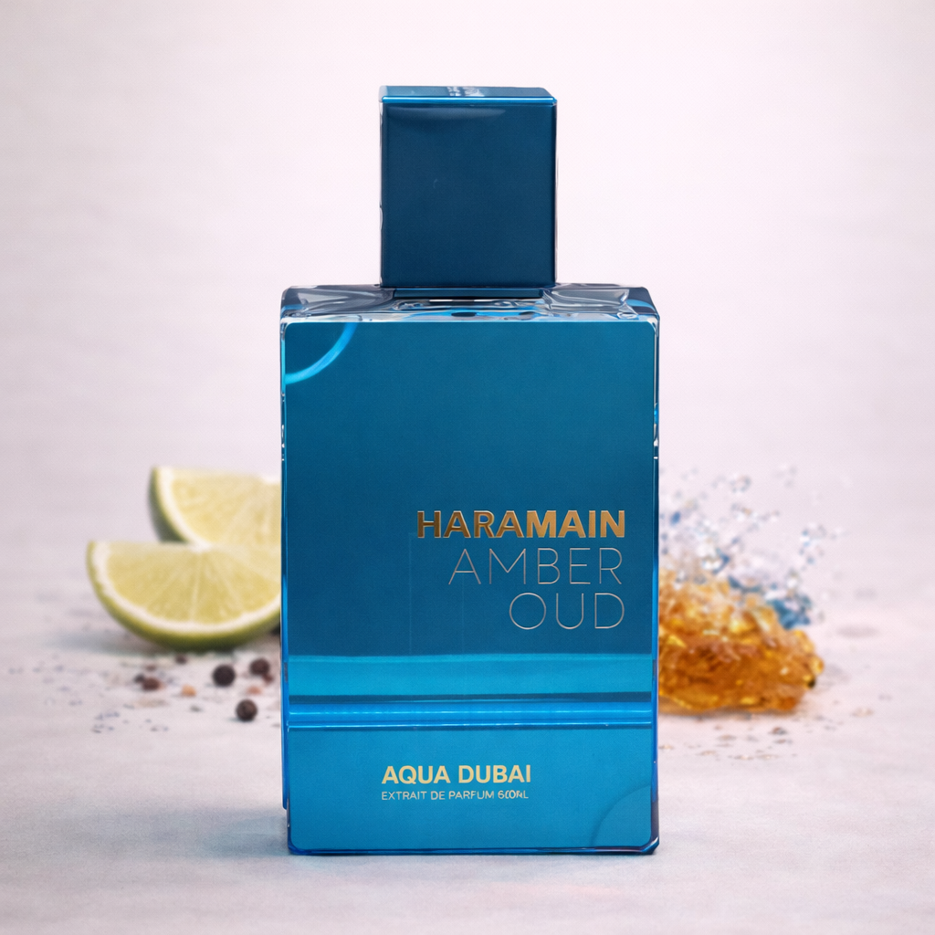 Blue perfume bottle labeled 'Haramain Amber Oud Aqua Dubai' on a light background with lime and honey.