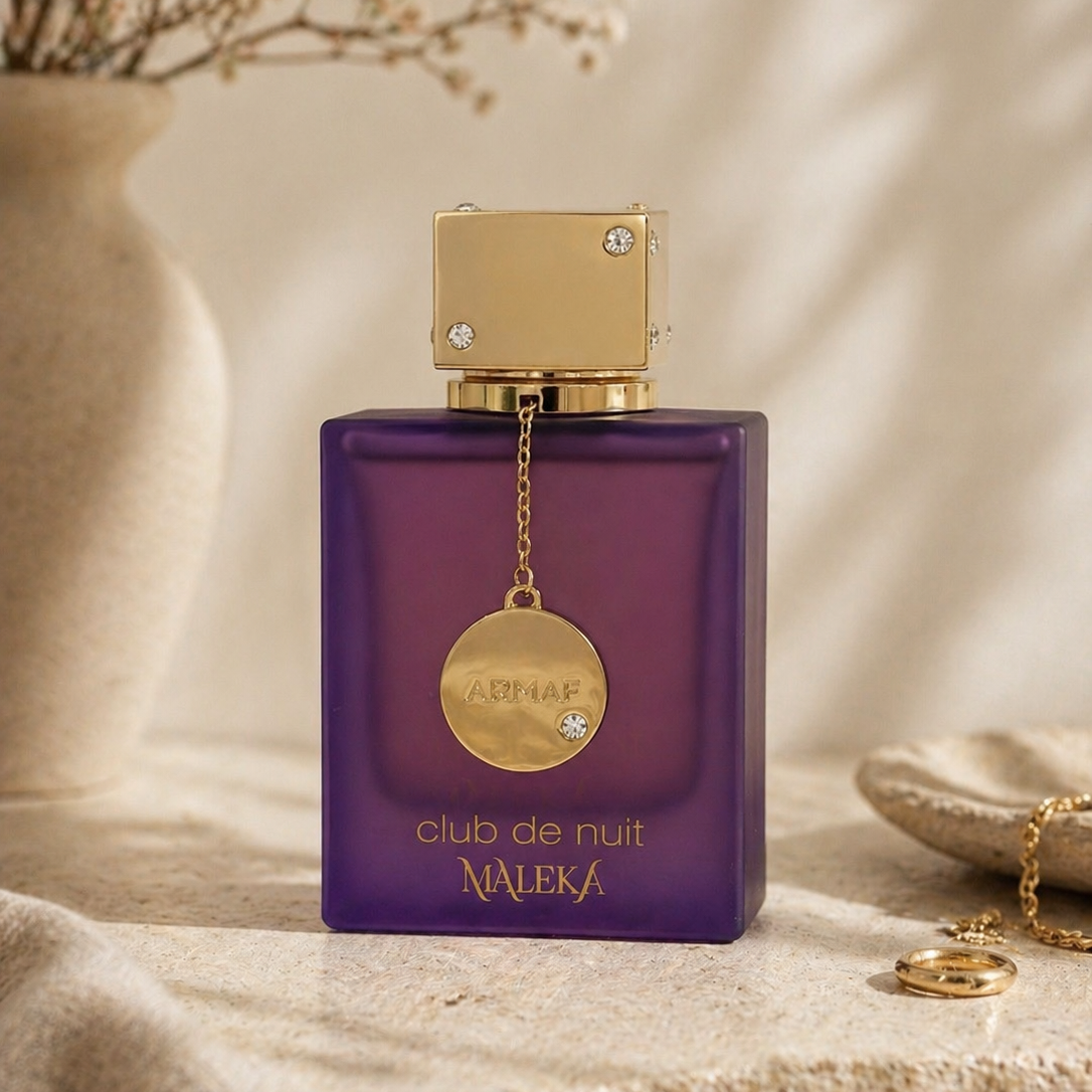Purple perfume bottle with gold cap and chain on a beige surface