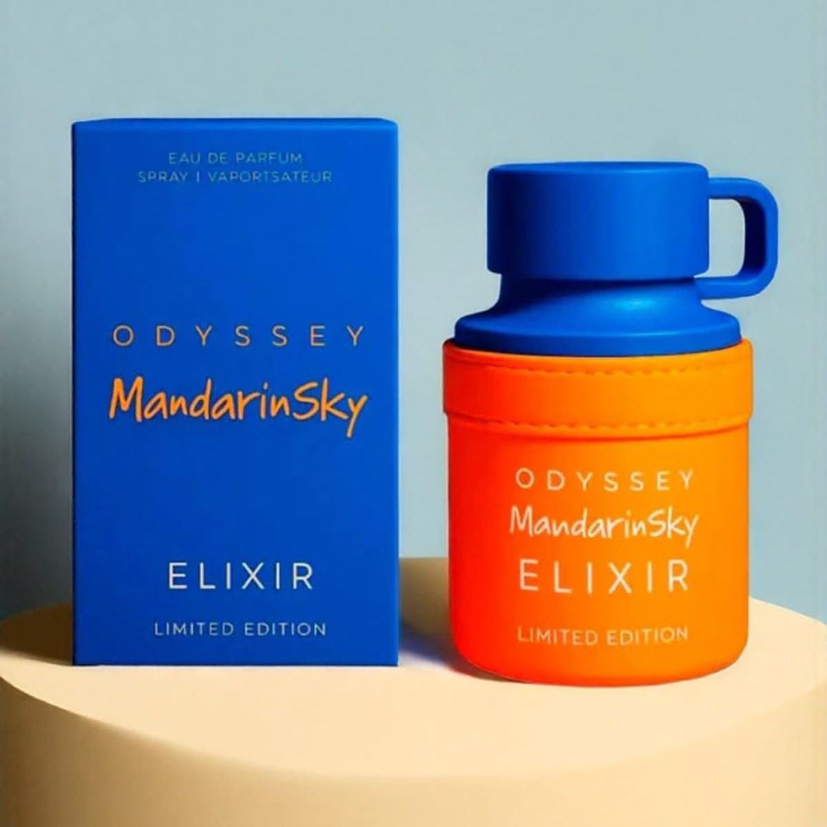 Orange and blue Odyssey Mandarin Sky Elixir perfume bottle and packaging on a beige surface with a light blue background.