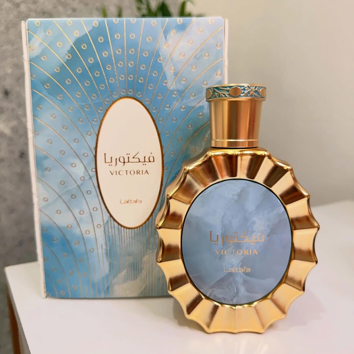 Gold perfume bottle with decorative packaging on a light surface